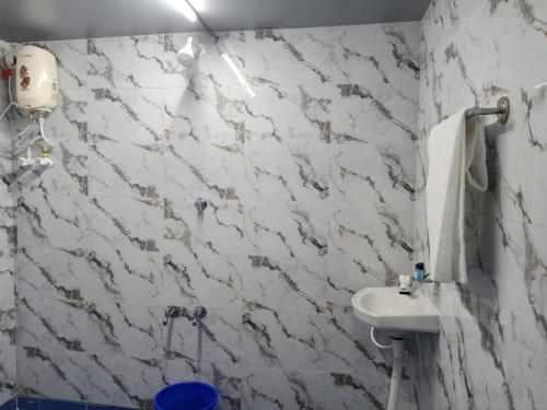 a bathroom with a sink and a white marble wall at Chan Beach Resort & Hotel in Bahūr