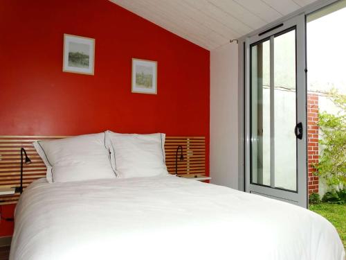 ein Schlafzimmer mit einem weißen Bett und einer roten Wand in der Unterkunft Petite Barque Saint Gilles Croix de Vie in Saint-Gilles-Croix-de-Vie