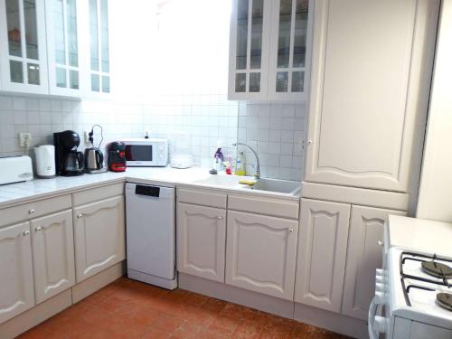 a white kitchen with a sink and a microwave at Le Mistral Saint Gilles Croix de Vie in Les Bussolleries