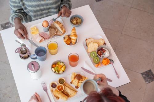 a group of people eating breakfast on a white table at Grand Hôtel Niort Centre in Niort