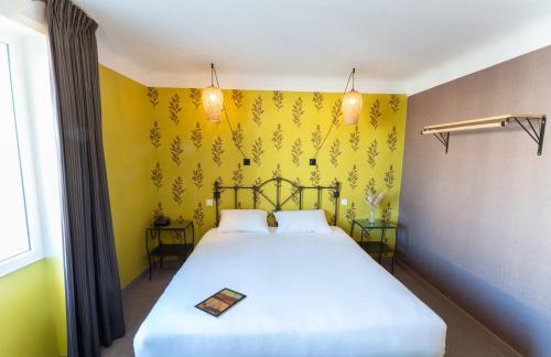 a bedroom with a large white bed with yellow walls at Grand Hôtel Niort Centre in Niort