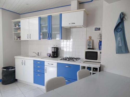 - une cuisine avec des placards bleus et blancs et un four micro-ondes dans l'établissement Maison Saint Gilles Croix de Vie - L'Embellie, à Saint-Gilles-Croix-de-Vie