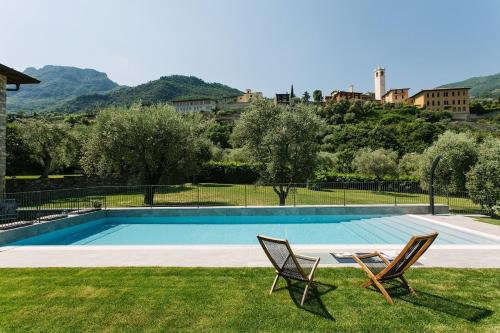 a swimming pool with two chairs in the grass at PELACA' Resort in Gargnano