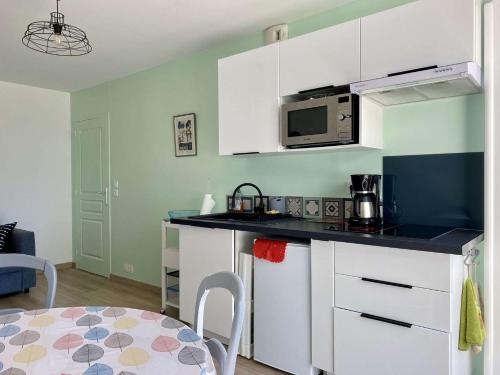 une cuisine avec des armoires blanches et une table dans une pièce dans l'établissement Phare Saint Gilles Croix de Vie, à Saint-Gilles-Croix-de-Vie