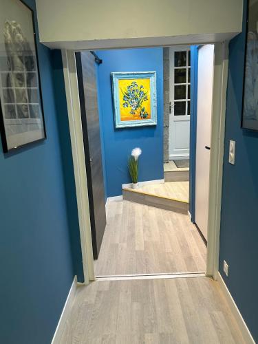 un couloir avec des murs bleus et une peinture murale dans l'établissement Appartement de charme, à Gavray