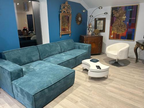 un salon avec un canapé bleu et une table dans l'établissement Appartement de charme, à Gavray