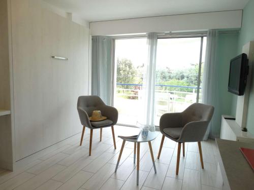 - deux chaises et une table dans une chambre avec fenêtre dans l'établissement Toile Saint Gilles Croix de Vie, à Saint-Gilles-Croix-de-Vie