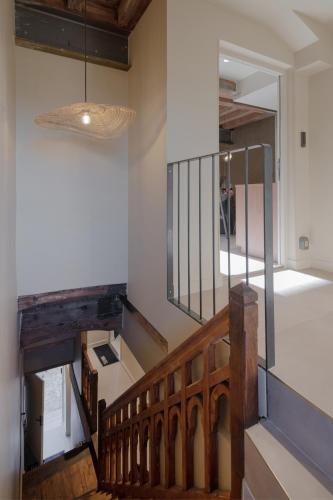 a hallway with a wooden staircase with a pendant light at MiHotel - Grenier à Sel de Pérouges in Pérouges
