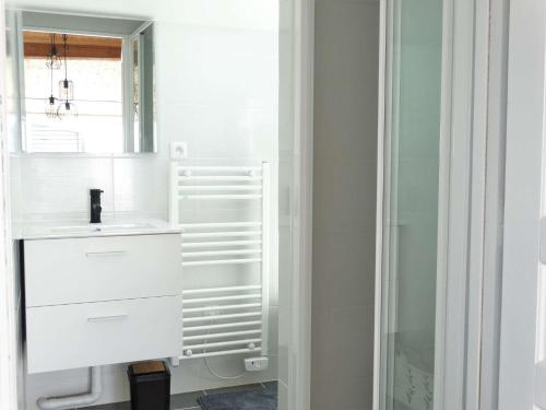 une salle de bain blanche avec un lavabo et un miroir dans l'établissement Crustacé Saint Hilaire de Riez, à Saint-Hilaire-de-Riez
