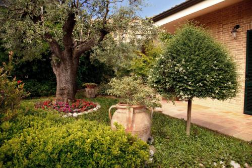 a garden with a tree and flowers in a yard at Ai Quattro Ulivi B&B in Monte Urano