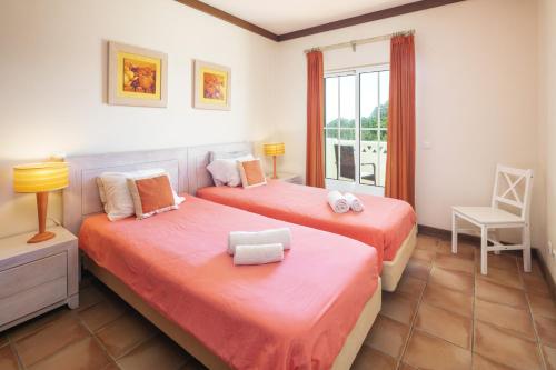 una camera da letto con due letti, una sedia e una finestra di 27 Terracos de Benagil - Casa Oceane a Benagil
