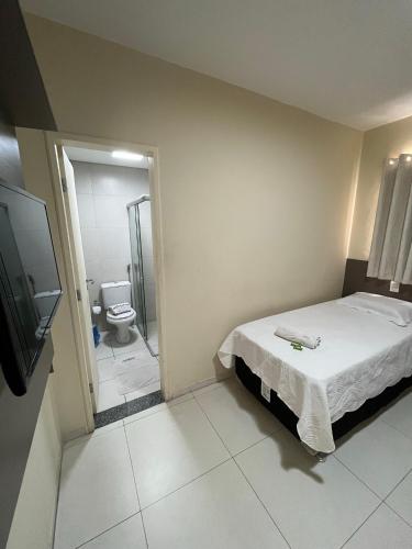a bedroom with a bed and a bathroom with a toilet at Grace Palace Hotel in Sobral