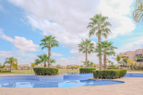 ein Resortpool mit Palmen im Hintergrund in der Unterkunft Luxury 2BD in Prestigia Jade with Pool and Golf View in Marrakesch
