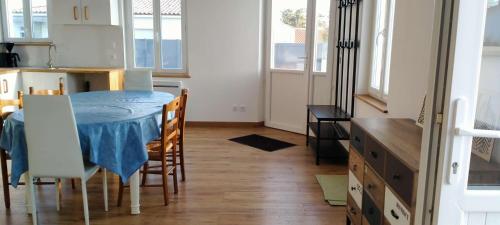 une cuisine et une salle à manger avec une table bleue et des chaises dans l'établissement L'évasion Littorale de Sion - Saint Hilaire de Riez, à Saint-Hilaire-de-Riez