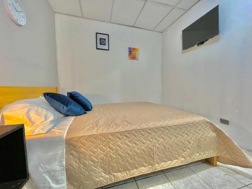 a bedroom with a bed with blue pillows and a tv at Yurrita Citadin in Guatemala