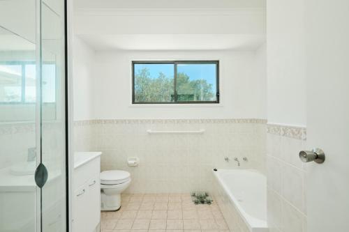 a bathroom with a tub and a toilet and a window at Salt and Pippies in Harrington