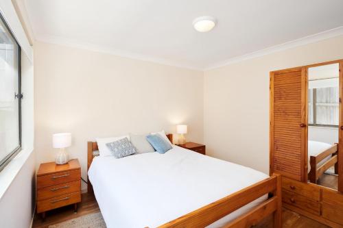 a white bedroom with a bed and a mirror at Salt and Pippies in Harrington