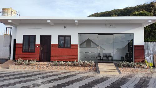 a white house with black doors and windows at Vaango Cottages in Idukki