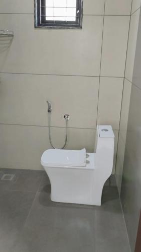 a white toilet in a bathroom with a window at Vaango Cottages in Idukki