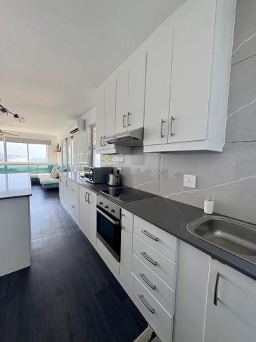 a kitchen with white cabinets and a black counter top at 92 Camarque - 3 Bedroom Apartment With Amazing Sea Views In Umdloti in Umdloti