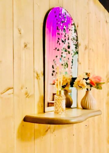 une étagère avec deux vases et un miroir fleuri dans l'établissement Le Tropikspa, à Albert