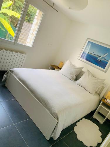 un lit blanc dans une chambre avec deux fenêtres dans l'établissement NEW renovated spacious 2 BR Apt AC 300m from Beach, à Juan-les-Pins