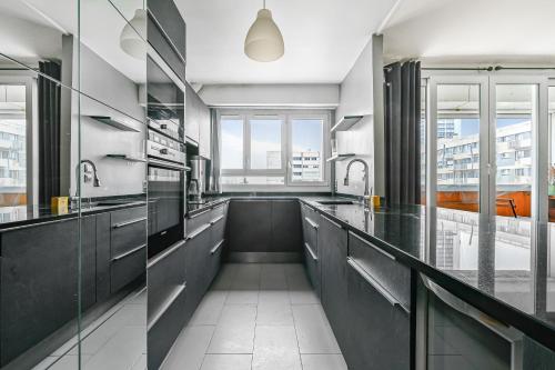 une grande cuisine avec comptoirs noirs et fenêtres dans l'établissement Le Spot - La Défense - Paris - Wifi, à Puteaux