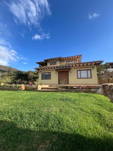 a house with a green lawn in front of it at Hotel Sol de la Montaña Villa de leyva in Villa de Leyva