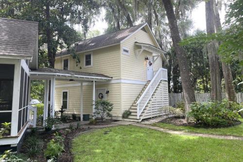 a woman standing on the stairs of a yellow house at Hickory Trace Carriage Studio in Bluffton