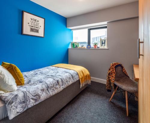 a bedroom with a blue wall and a bed and a chair at Steelworks at Copley Court in Cork