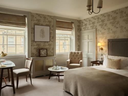 a bedroom with a bed and chairs and windows at The Queensberry Hotel in Bath