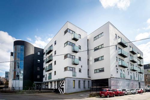 a white building with cars parked in a parking lot at Steelworks at Copley Court in Cork