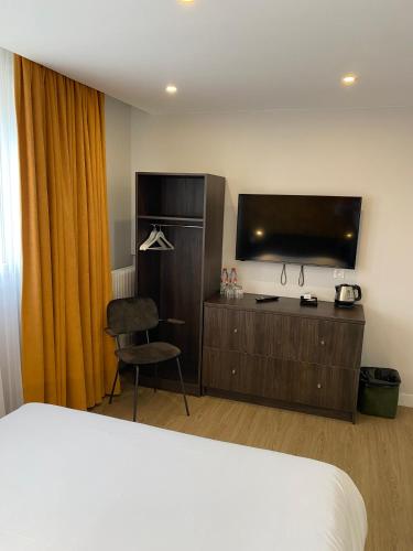 a hotel room with a bed and a flat screen tv at Hôtel Restaurant l'Annexe in Saint-Valéry-en-Caux