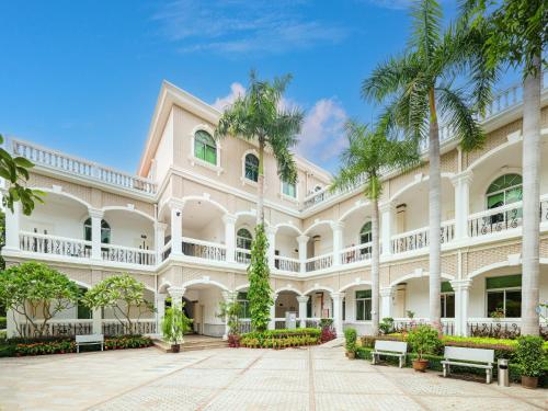 an exterior view of a large white building with palm trees at Xiamen Kulangsu Resort Hotel in Xiamen
