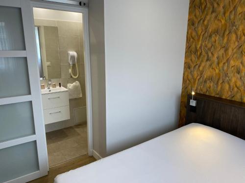 a bedroom with a bed and a bathroom with a mirror at Hôtel Restaurant l'Annexe in Saint-Valéry-en-Caux