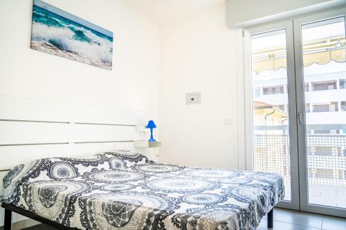 een slaapkamer met een bed en een groot raam bij Condominio Athena in Bibione