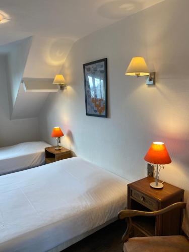 a bedroom with two beds and two lamps on tables at Hôtel Restaurant l'Annexe in Saint-Valéry-en-Caux