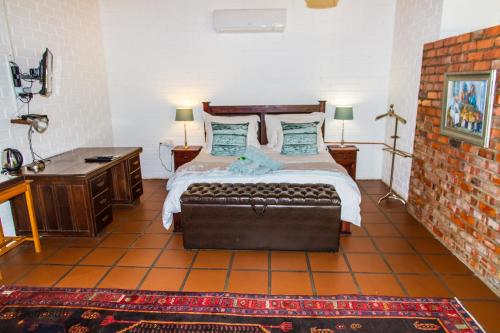 a bedroom with a large bed with a couch at Upington African Vineyard Boutique Hotel & SPA in Kanoneiland
