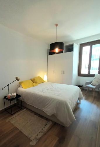 une chambre avec un grand lit blanc et une fenêtre dans l'établissement Appartement T2 40 m2 rue du casino centre-ville climatisé 1 chambre balcon, à Aix-les-Bains
