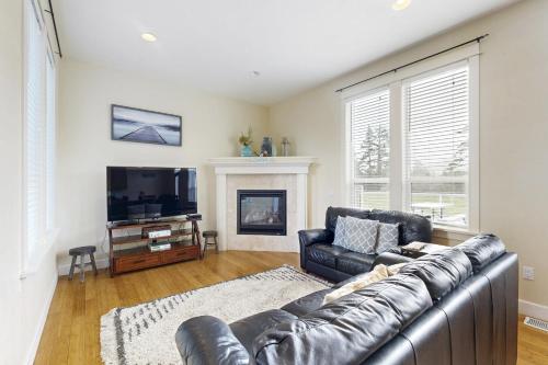a living room with a leather couch and a television at Fairway and Far Away in Seaside
