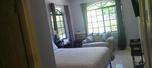 una camera con letto, sedia e finestre di Private Lodge, Cousin's Cove a Green Island