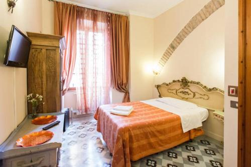 ローマにあるマルタ ゲスト ハウスのベッドとテレビが備わるホテルルームです。