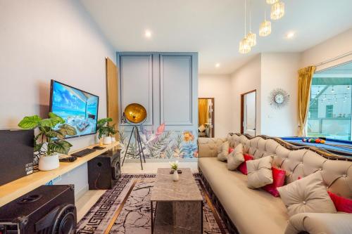 a living room with a couch and a tv at M4 Billion Pool Villa Cha-am in Cha Am