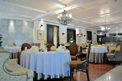 a restaurant with white tables and chairs and a chandelier at Rama Gardens Hotel Bangkok in Bangkok