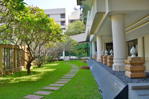 a building with a walkway next to a yard at Rama Gardens Hotel Bangkok in Bangkok