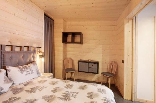 a bedroom with a bed and two chairs at Appartamenti I Portici in Santa Caterina Valfurva