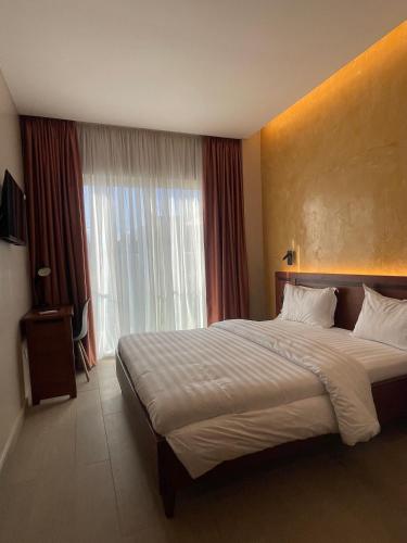 a bedroom with a large bed and a large window at NK Hotel Lagrace in Yaoundé