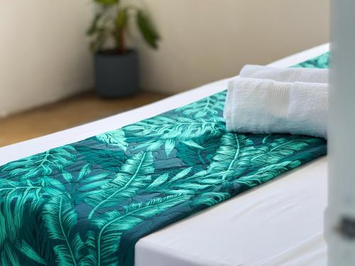a bed with a green and white comforter and towels at Villa Océan Gravier Rodrigues in Mt Bois Noir