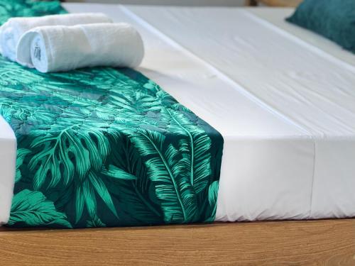 a bed with a green and white blanket and towels at Villa Océan Gravier Rodrigues in Mt Bois Noir