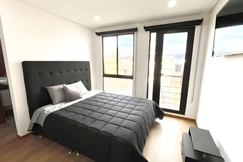 a bedroom with a black bed and large windows at Edificio Urban in Cajicá